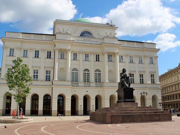 A classicist, bright, impressive palace with arcades and columns. In front of the entrance, there is a monument to Copernicus
