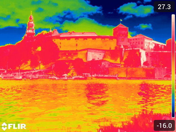 Thermal image of a castle by a river; the castle appears red-orange, while the sky is deep blue