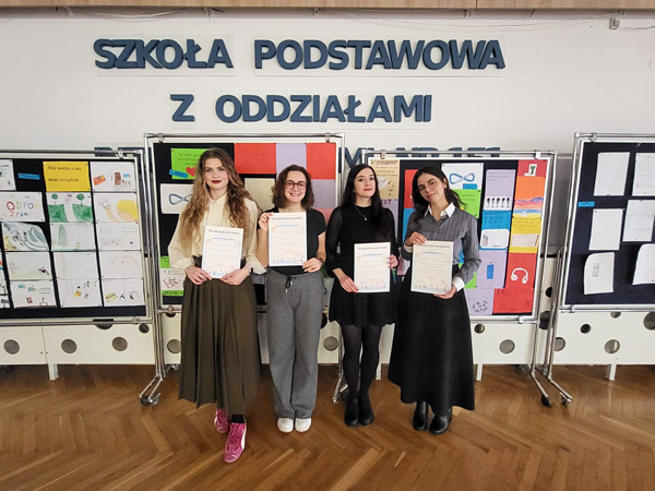 Four young women stand side by side, posing for a photo and holding commemorative certificates of appreciation