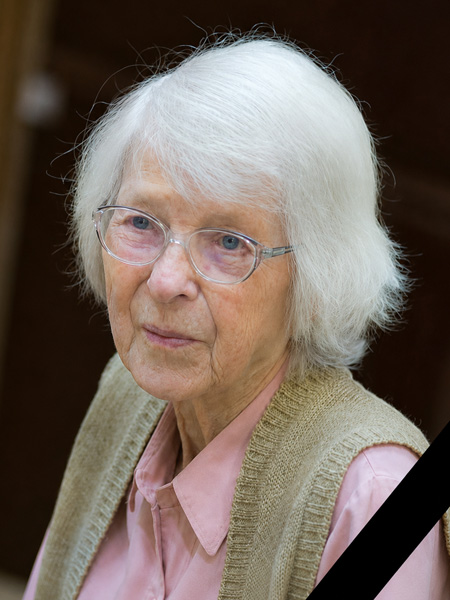 Portrait of an elderly slim woman with glasses and grey, almost white hair